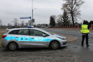 Zdjęcie przedstawia policjanta i radiowóz.