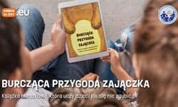 Dzieci trzymają w dłoniach książkę &quot;Burcząca przygoda zajączka&quot;