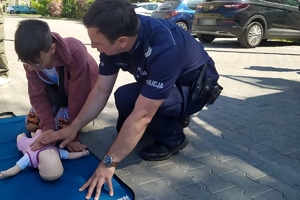 Zdjęcie przedstawia policjanta prezentującego pierwsza pomoc na fantomie.