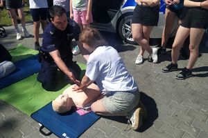 Zdjęcie przedstawia policjanta prezentującego pierwsza pomoc na fantomie.