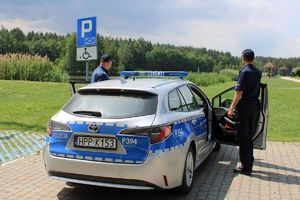 Policjanci obok radiowozu nad zalewem.