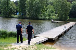 Policjanci idą kładką nad zalewem.