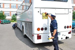 Zdjęcie przedstawia policjantów ruchu drogowego podczas kontroli autokaru przewożącego dzieci.