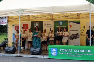 Zdjęcie przedstawia namiot ze sceną, na której znajduje się grupa dzieci oraz Dyrektor Kuratorium Oświaty Delegatury w Częstochowie.