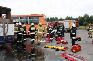 Zdjęcie przedstawia miejsce wypadku, autokary, wozy strażackie, strażaków i policjantów.