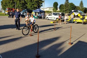 Zdjęcie przedstawia mobilne miasteczko ruchu drogowego, chłopca na rowerze oraz policjanta.