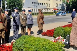 Zdjęcie przedstawia przedstawicieli służb mundurowych i instytucji z powiatu kłobuckiego pod pomnikiem.