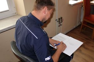 Zdjęcie przedstawia policjanta rozwiązującego test.
