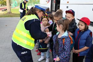 Zdjęcie przedstawia policjantkę, która rozdaje dzieciom odblaski.