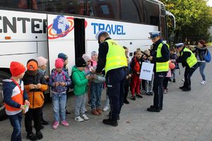 Zdjęcie przedstawia policjantów rozdających dzieciom odblaski.