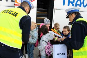 Zdjęcie przedstawia policjantów rozdających dzieciom odblaski.