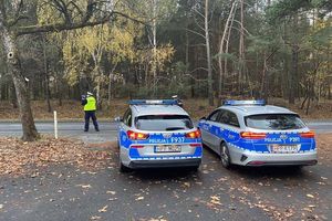 Zdjęcie przedstawia dwa radiowozy oraz policjantów mierzących prędkość nadjeżdżającym pojazdom.