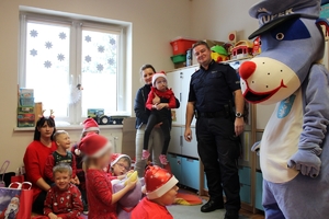 Zdjęcie przedstawia policjanta, Sznupka oraz dzieci i opiekunów pozujących do zdjęcia.