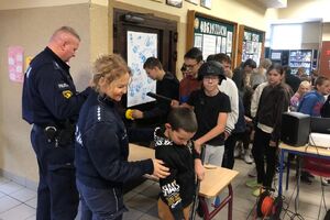 Zdjęcie przedstawia policjantkę i policjanta prezentujących dzieciom sprzęt służbowy.