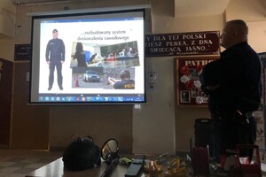 Zdjęcie przedstawia policjanta oraz dzieci podczas projekcji.