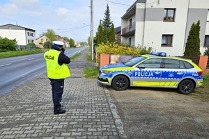 Zdjęcie przedstawia policjanta ruchu drogowego oraz radiowóz.