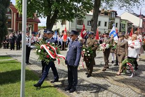 Zdjęcie przedstawia przedstawicieli służb mundurowych oraz innych uczestników uroczystości podczas składania wiązanek.