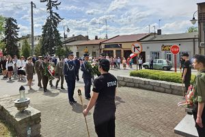 Zdjęcie przedstawia przedstawicieli służb mundurowych oraz innych uczestników uroczystości podczas składania wiązanek.