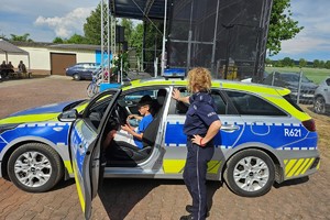 Zdjęcie przedstawia chłopca w radiowozie oraz policjantkę.