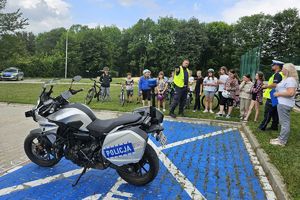 Zdjęcie przedstawia policyjny motocykl, policjantów oraz dzieci z rowerami.