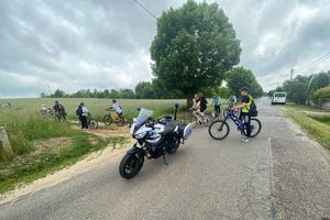 Zdjęcie przedstawia rowerzystów oraz policyjny motocykl.