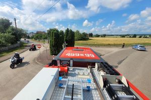 Zdjęcie przedstawia widok na skrzyżowanie, policyjny motocykl oraz radiowóz z dachu wozu strażackiego.