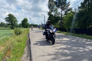 Zdjęcie przedstawia policyjny motocykl oraz biegaczy.