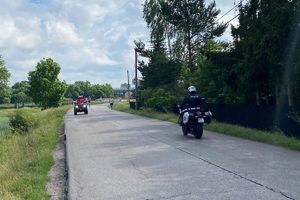 Zdjęcie przedstawia policyjny motocykl oraz biegaczy.