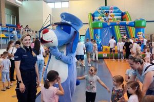 Zdjęcie przedstawia policjantkę, Sznupka oraz uczestników pikniku w hali.