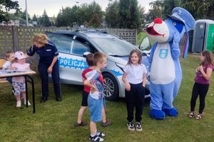 Zdjęcie przedstawia policjantkę, Sznupka oraz uczestników pikniku.