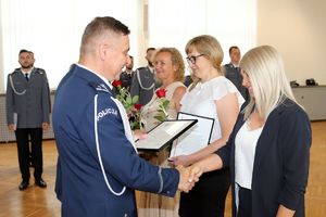 Zdjęcie przedstawia komendantów wręczających listy gratulacyjne pracownikom.