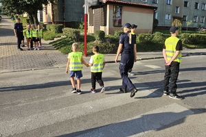 Zdjęcie przedstawia uczniów oraz policjantki przechodzących przez oznakowane przejście dla pieszych.