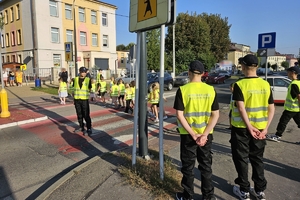 Zdjęcie przedstawia uczniów oraz policjantki przechodzących przez oznakowane przejście dla pieszych.