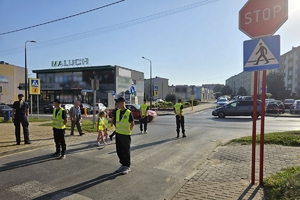 Zdjęcie przedstawia uczniów oraz policjantki przechodzących przez oznakowane przejście dla pieszych.