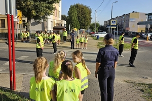 Zdjęcie przedstawia uczniów oraz policjantki przechodzących przez oznakowane przejście dla pieszych.