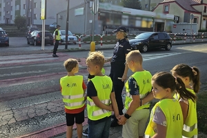 Zdjęcie przedstawia uczniów oraz policjantki przechodzących przez oznakowane przejście dla pieszych.