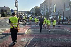 Zdjęcie przedstawia uczniów oraz policjantki przechodzących przez oznakowane przejście dla pieszych.