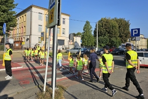 Zdjęcie przedstawia uczniów oraz policjantki przechodzących przez oznakowane przejście dla pieszych.