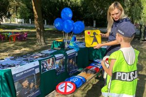 Zdjęcie przedstawia policjantkę prezentująca znak ruchu drogowego dzieciom.