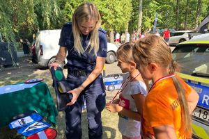 Zdjęcie przedstawia policjantkę prezentująca znak ruchu drogowego dzieciom.