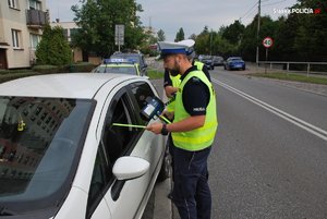 Zdjęcie przedstawia policjanta dokonującego kontroli pojazdu.