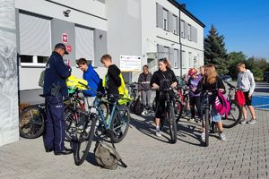 Zdjęcie przedstawia policjanta oraz grupę rowerzystów.