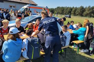 Zdjęcie przedstawia policjantkę oraz grupę dzieci siedzących przy stoliku.