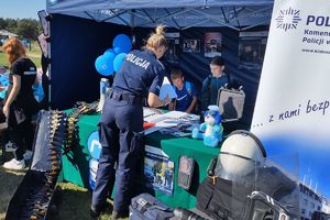 Zdjęcie przedstawia policjantkę oraz dzieci przy stoisku policyjnym.