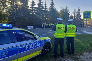 Zdjęcie przedstawia policjantów, radiowóz oraz protestujących.