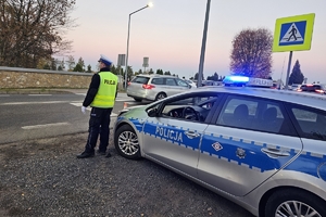 Zdjęcie przedstawia policjanta oraz radiowóz.