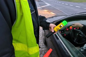 Zdjęcie przedstawia policjanta z urządzeniem do badania stanu trzeźwości.