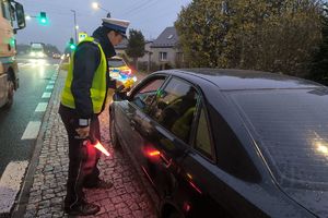 Zdjęcie przedstawia policjanta kontrolującego stan trzeźwości kierowcy.