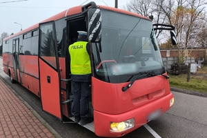 Zdjęcie przedstawia policjanta wchodzącego do autobusu.