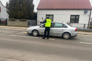 Zdjęcie przedstawia policjanta kontrolującego stan trzeźwości kierowcy.